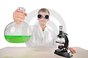 Scientist boy in black glasses holds a big flask fith green foaming fluid