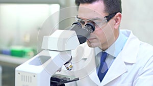 Scientist carries out scientific research looking through microscope in a medical laboratory.