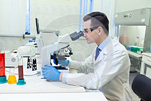 Scientist carries out scientific research looking through microscope in a medical laboratory.