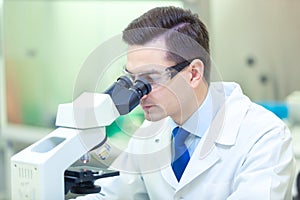 Scientist carries out scientific research looking through microscope in a medical laboratory. COVID-19. COVID