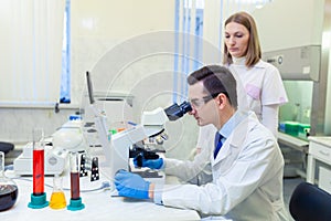 Scientist carries out scientific research looking through microscope in a medical laboratory. Scientist with an