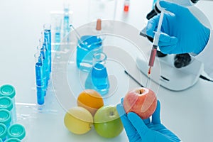 Scientist check chemical food residues in laboratory. Control experts inspect quality of fruit, scientists inject chemicals into