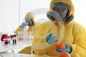 Scientist in chemical protective suit injecting orange, space for text