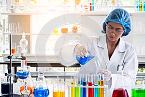 Scientist or chemist pouring blue liquid substance into test tube, doing science experiment at laboratory .