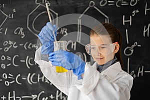 scientist child with glasses in lab coat with chemical flask, little student on chemistry lesson in lab doing an
