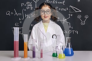Scientist child in lab coat with chemical flasks