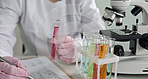 Scientist conducting experiments with test tubes and microscope in a laboratory