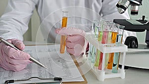Scientist conducting experiments with test tubes and microscope in laboratory