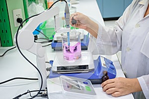 Scientist dropping fluid to sample in beaker