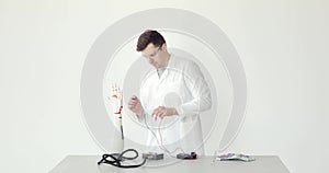 Scientist engineer connects and configures robotic prosthesis hand on the table on white background.