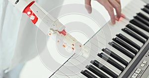 Scientist engineer is tasting robotic prosthesis hand playing the piano trying to press the right keys.