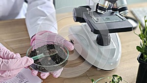 Scientist examines soil sample using microscope in laboratory