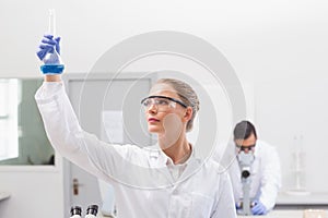 Scientist examining blue precipitate in baker