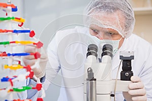 Scientist examining dna helix and looking in microscope