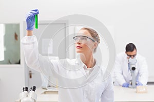 Scientist examining green precipitate in tube