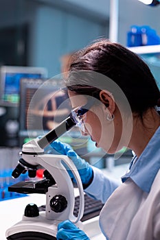 Scientist examining researching analyzing virus loking through microscope