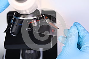 Scientist examining sample on slide under microscope, closeup