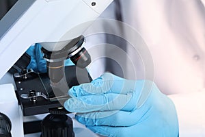 Scientist examining sample on slide under microscope, closeup