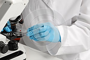 Scientist examining sample on slide under microscope, closeup