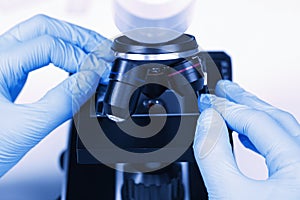 Scientist examining sample on slide under microscope, closeup