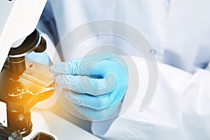 Scientist examining sample on slide under microscope, closeup