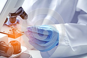 Scientist examining sample on slide under microscope, closeup