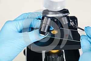 Scientist examining sample on slide under microscope, closeup