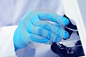 Scientist examining sample on slide under microscope, closeup