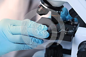 Scientist examining sample on slide under microscope, closeup