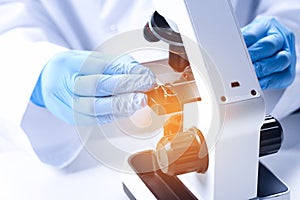 Scientist examining sample on slide under microscope at table, closeup