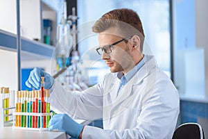 Scientist in eyeglasses working with test tubes in lab