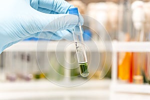 Scientist fingers holding a glass test tube in a research lab