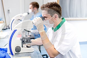 Scientist and forensic analyser working with microscope