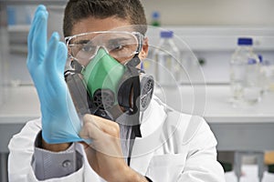 Scientist In Gas Mask And Putting On Rubber Glove