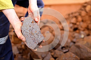 Scientist geologist hands inspecting exploration on iron ore rock on open field mine site