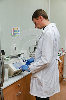 Scientist with gloved hand putting DNA sample into real-time PCR-cycler photo