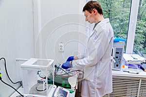 Scientist with gloved hand putting DNA sample into real-time PCR-cycler photo