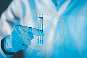 Scientist hand hold test tubes filled with blue sample chemicals in chemistry science laboratory. Glassware in medical research.