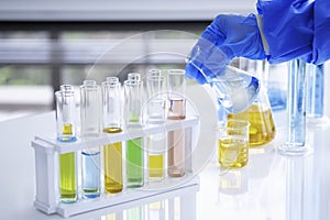 The scientist is hand holds a beaker of chemicals in the lab to prepare specimens to test