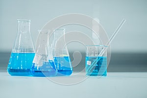 Scientist hand titration with burette and erlenmeyer flask, science laboratory research and development concept. Biology, liquid.