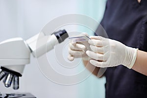 Scientist hands holding samples liquid with microscope on background