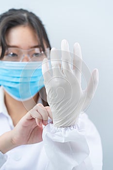 Scientist hands putting in nitrile gloves in labcoat wearing nitrile gloves