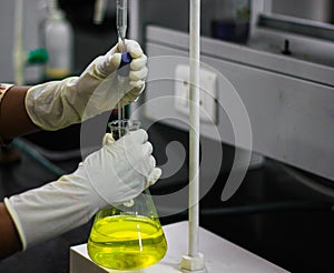 Scientist holding albuminometer containing yellow solution with a cork a gloved hand in chemistry laboratory