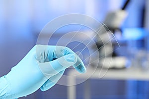 Scientist holding clean glass microscope slides in laboratory, closeup