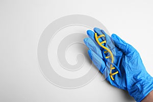 Scientist holding DNA molecule model made of colorful plasticine on white background, top view. Space for text