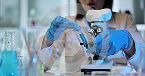 Scientist holding and looking at a test tube with blue liquid in the laboratory