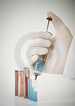 Scientist holding old injection with blue chemical.