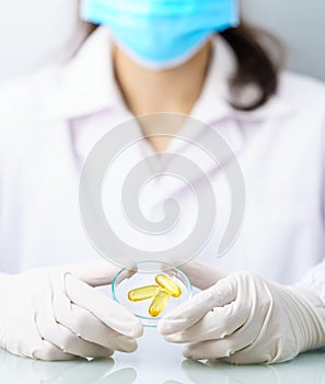 Scientist holding Omega 3 capsule in labcoat