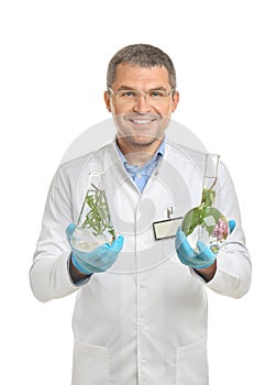 Scientist holding test flasks with plants on white background