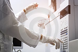 scientist holds an amber vial and press the control button of GC chromatography